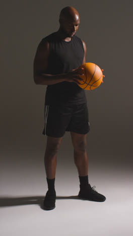 Vertical-Video-Full-Length-Studio-Shot-Of-Male-Basketball-Player-Throwing-Ball-From-One-Hand-To-The-Other